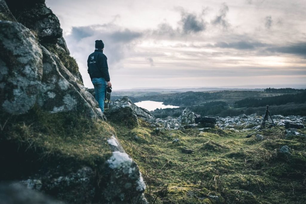 Man standing in the Dartmoor national park while wild camping looking out into the view.