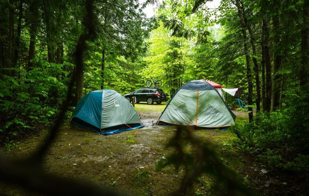 Image of people camping in the rain with 2 tents already pitched up